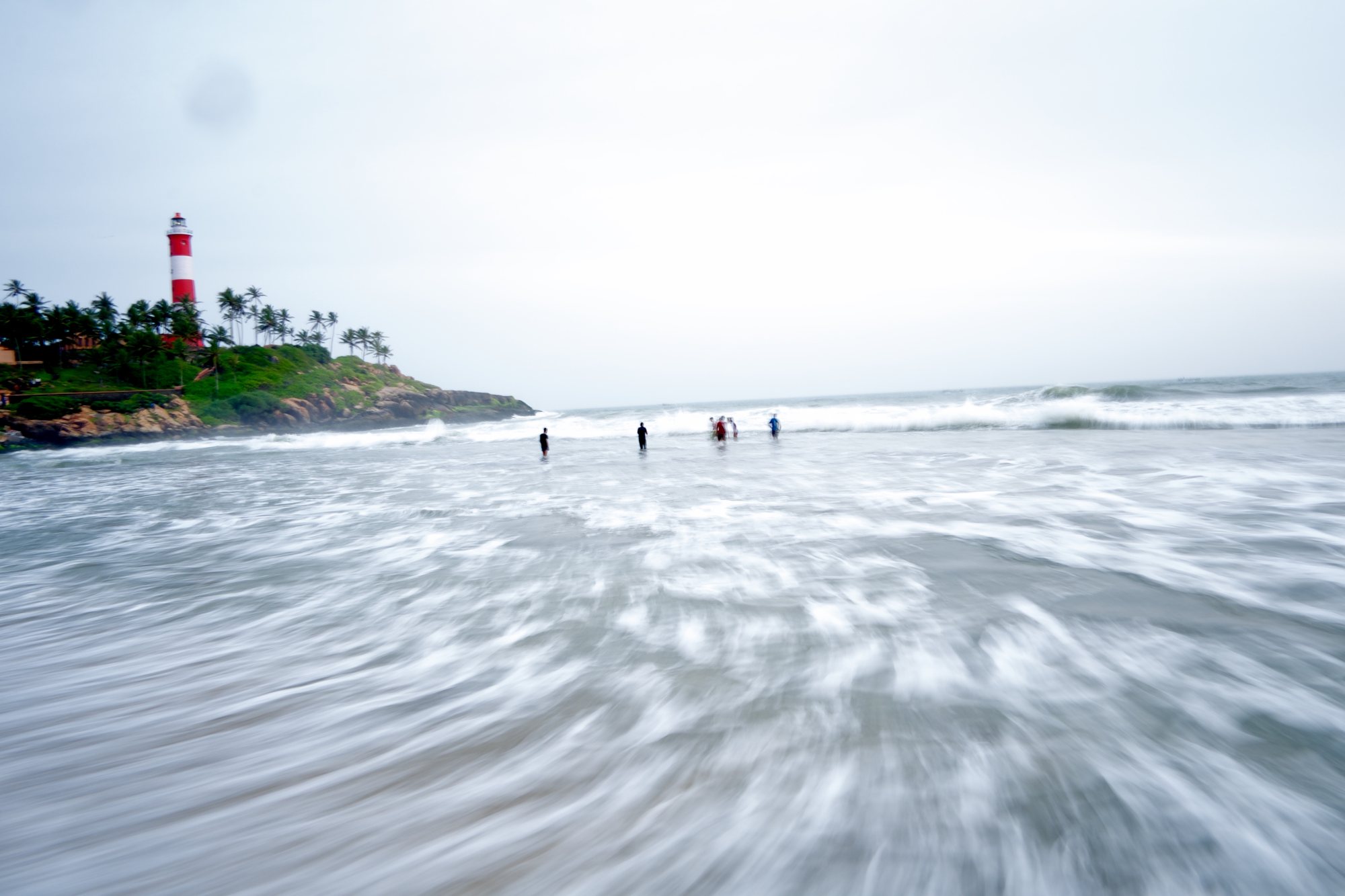 Baigneurs face à un phare, Kerala, Inde