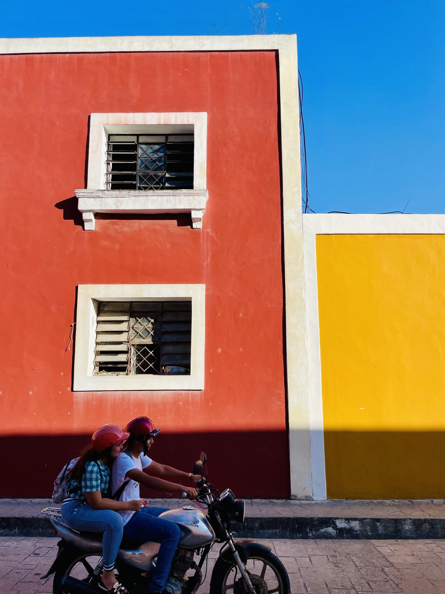 Couple en scooter devant une façade colorée, Mexique